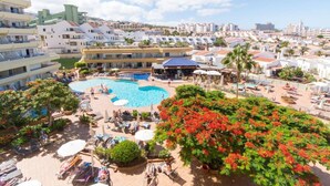Een resort met een groot zwembad, ligbedden en uitzicht op de omliggende stad.