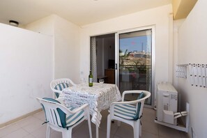 A balcony with a table, chairs, a bottle, and a small air conditioning unit.