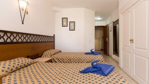 Une chambre d’hôtel avec deux lits, une armoire et un luminaire fixé au mur.
