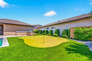 A backyard with a swimming pool, a barbecue area, and a well-maintained lawn.