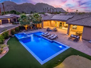 A residential property with a swimming pool, patio furniture, and a view of mountains.