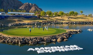 A golf course with a pond, a mountain in the background, and the text 'AMERICAN EXPRESS' on the water. - PGA West: Your Poolside & Fire Pit Haven (La Quinta)