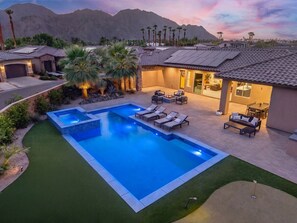 A residential property with a swimming pool, outdoor seating, and a mountain backdrop.