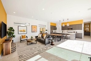 A modern living room with a sofa, coffee table, and a dining area with chairs.
