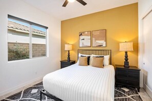 A bedroom with a bed, two bedside tables, a window, and a ceiling fan. - PGA West: Your Poolside & Fire Pit Haven (La Quinta)