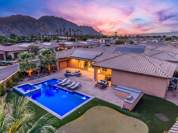A residential area with a swimming pool, patio furniture, and a view of mountains.