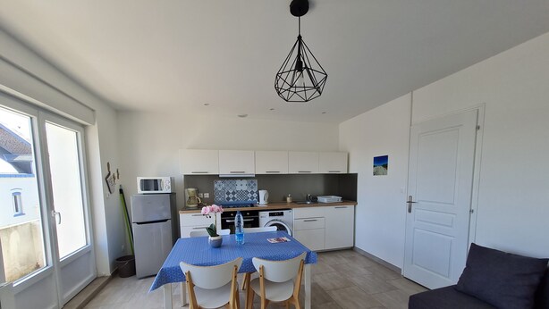 Una cocina compacta con una mesa de comedor, sillas, un sofá y una lámpara colgante.