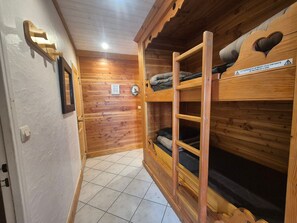 Un interior de madera con literas, una puerta con interruptor de luz y un cartel de advertencia.