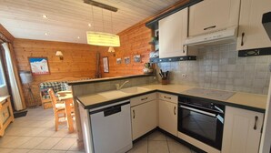Eine kleine Küche mit Holzwänden, einem Geschirrspüler, einem Backofen und einem Spülbecken.