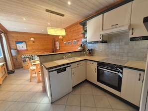 A compact kitchen with wooden walls, a dishwasher, an oven, and a sink.