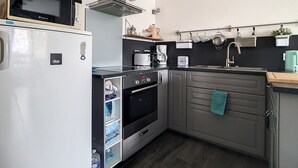 Een kleine keuken met een koelkast, oven, magnetron en koffiezetapparaat.