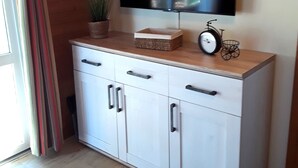 Un meuble blanc avec des tiroirs, et un téléviseur fixé au mur au-dessus.