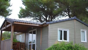 Une petite cabane à un seul étage, dotée d’une véranda, d’une porte-fenêtre coulissante et d’une fenêtre.