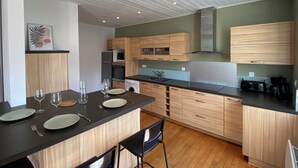 Une cuisine moderne avec des meubles en bois, un plan de travail noir et un coin repas comprenant des chaises et de la vaisselle.