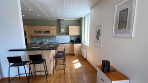 Une cuisine moderne avec des meubles en bois, un îlot central doté de tabourets de bar et un radiateur blanc.