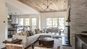 Un amplio salón con un sofá seccional grande, una mesa de comedor con sillas y una cocina al fondo.