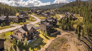 Un barrio residencial con casas modernas, un camino sinuoso y un bosque al fondo.