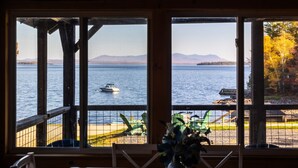 A view from a cabin with large windows overlooking a lake, a boat, and distant mountains. - Sleeps 25! Book all 5 Lawrence`s Lakeside Cabins! (Rockwood)