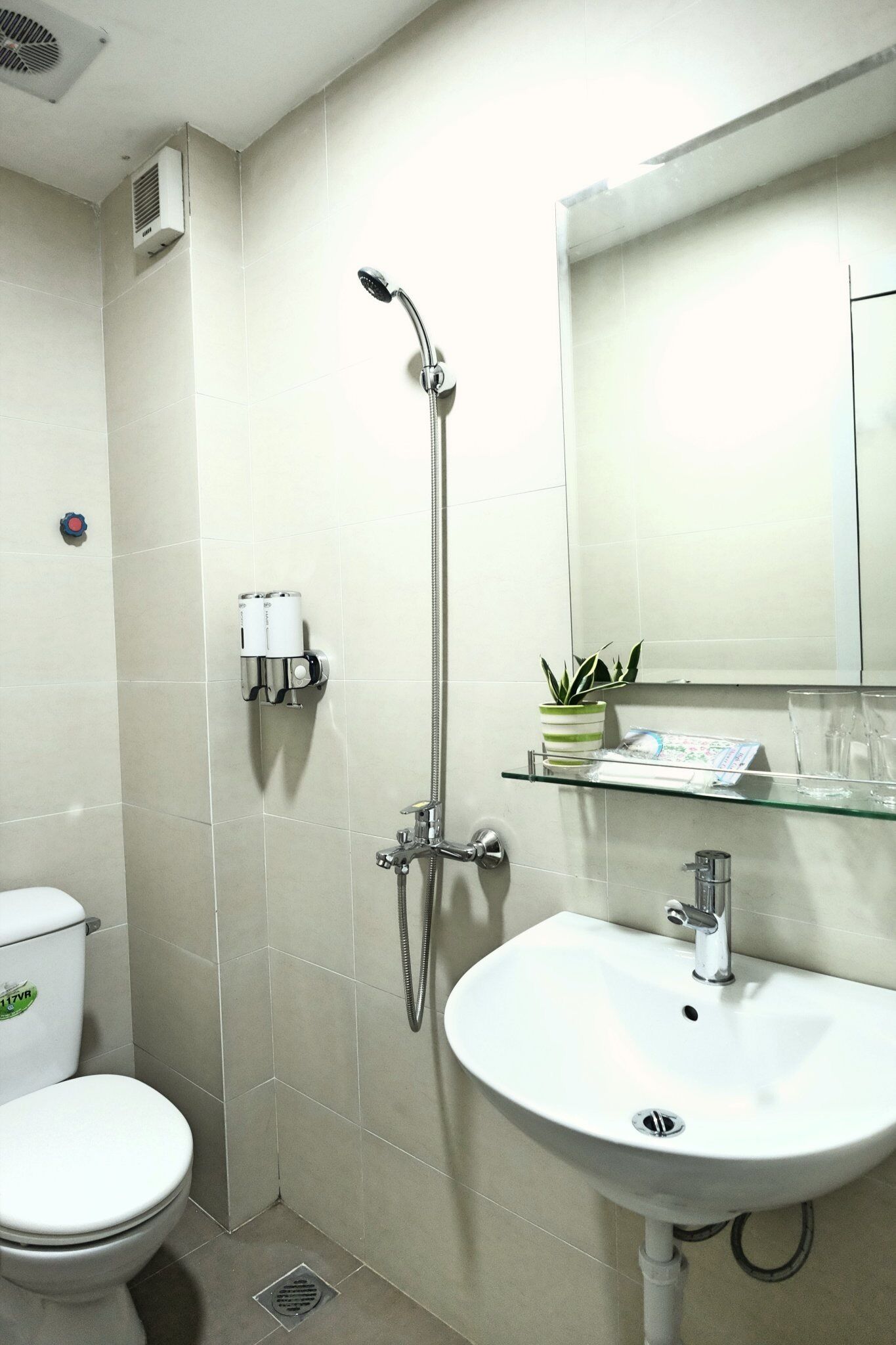 A bathroom with a toilet, a sink, a shower, and a mirror.
