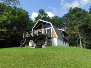Une maison moderne avec un toit en pente, une terrasse en bois et des fondations en pierre.