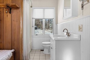 Une salle de bain avec des toilettes, un lavabo et une fenêtre équipée de stores.
