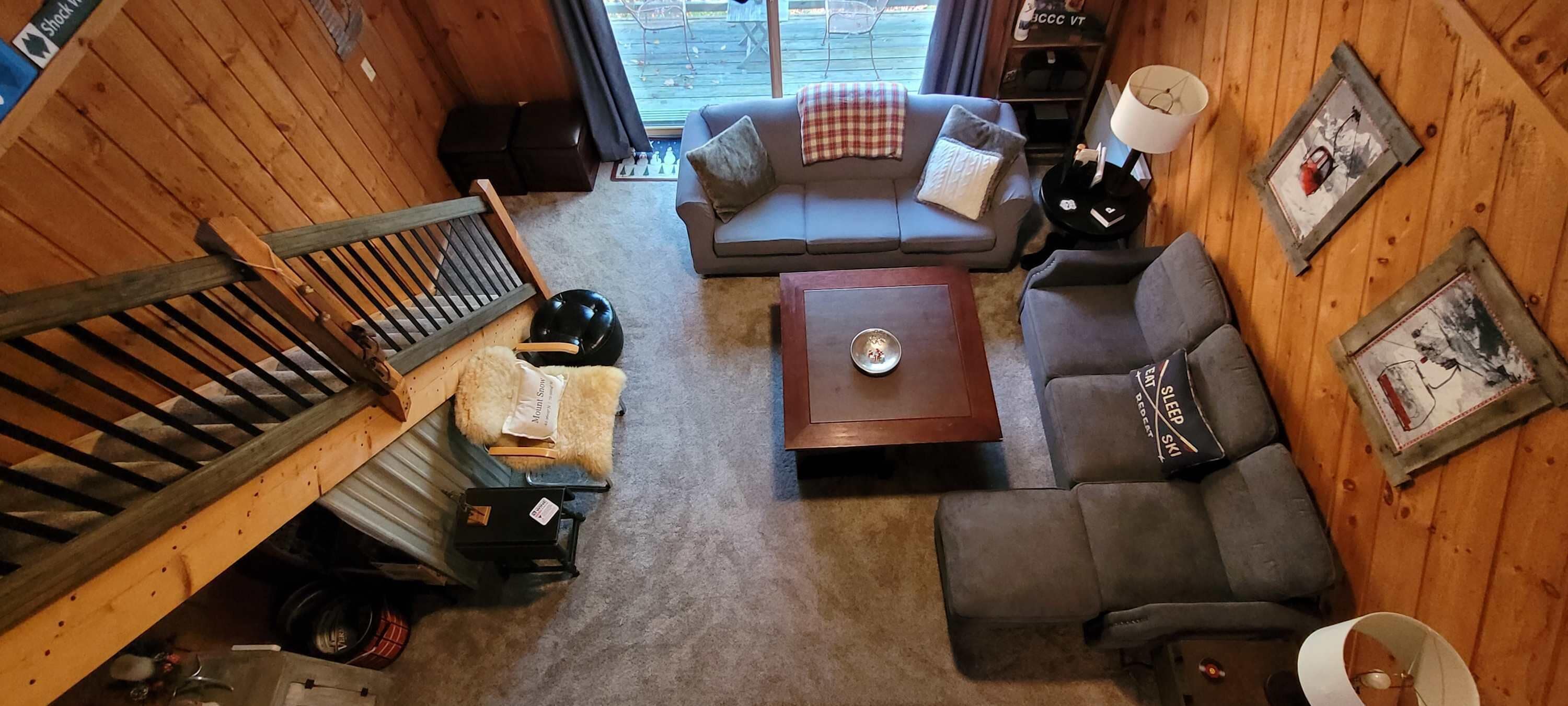 A cozy cabin-style room with a wooden interior, a sofa, a coffee table, and a staircase.