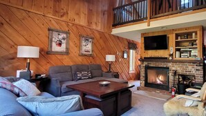 A cozy living room with a fireplace, wooden walls, and a comfortable seating area.