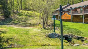 A lodge named 'Ski Trail' with a wooden exterior, a covered porch, and a grassy area with trees in the background.