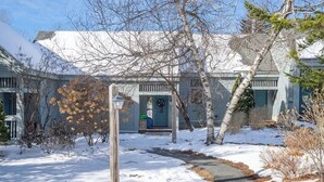 A snow-covered residential area with a pathway leading to a house with a porch. - Updated Condo Close to Mt Snow! (Wilmington)