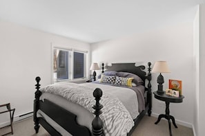 Une chambre à coucher avec un lit, deux tables de chevet, une fenêtre et une porte.