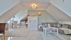 A spacious loft with a high ceiling, a dining area, and a cozy seating area with a sofa and coffee table. - Domizil am Eschenweg 5 Appartement Ostseerauschen (Scharbeutz)
