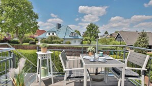An outdoor deck with a table and chairs, surrounded by a hedge and trees. - Domizil am Eschenweg 5 Appartement Ostseerauschen (Scharbeutz)
