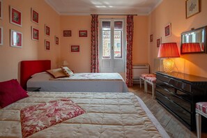 A bedroom with two beds, a dresser, a radiator, and a window with curtains. - Casa Golena (Venezia)