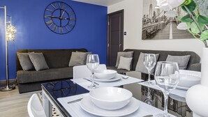 A modern living room with a blue accent wall, a large clock, and a cityscape painting.