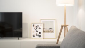 A modern living room with a flat-screen TV, two framed artworks, and a floor lamp. - Oasis de Luxe au Cœur de Grenade: Appartement Moderne, Proche Alhambra, Wi-Fi Gratuit, 2 Chambres (Granada)