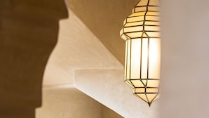 Un intérieur moderne agrémenté d’un luminaire suspendu aux formes géométriques et d’un tableau représentant un paysage urbain encadré.