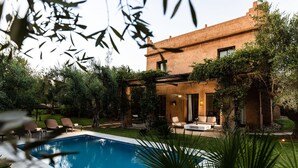 Une maison moderne dotée d’une piscine, d’un espace salon extérieur et d’une végétation luxuriante.