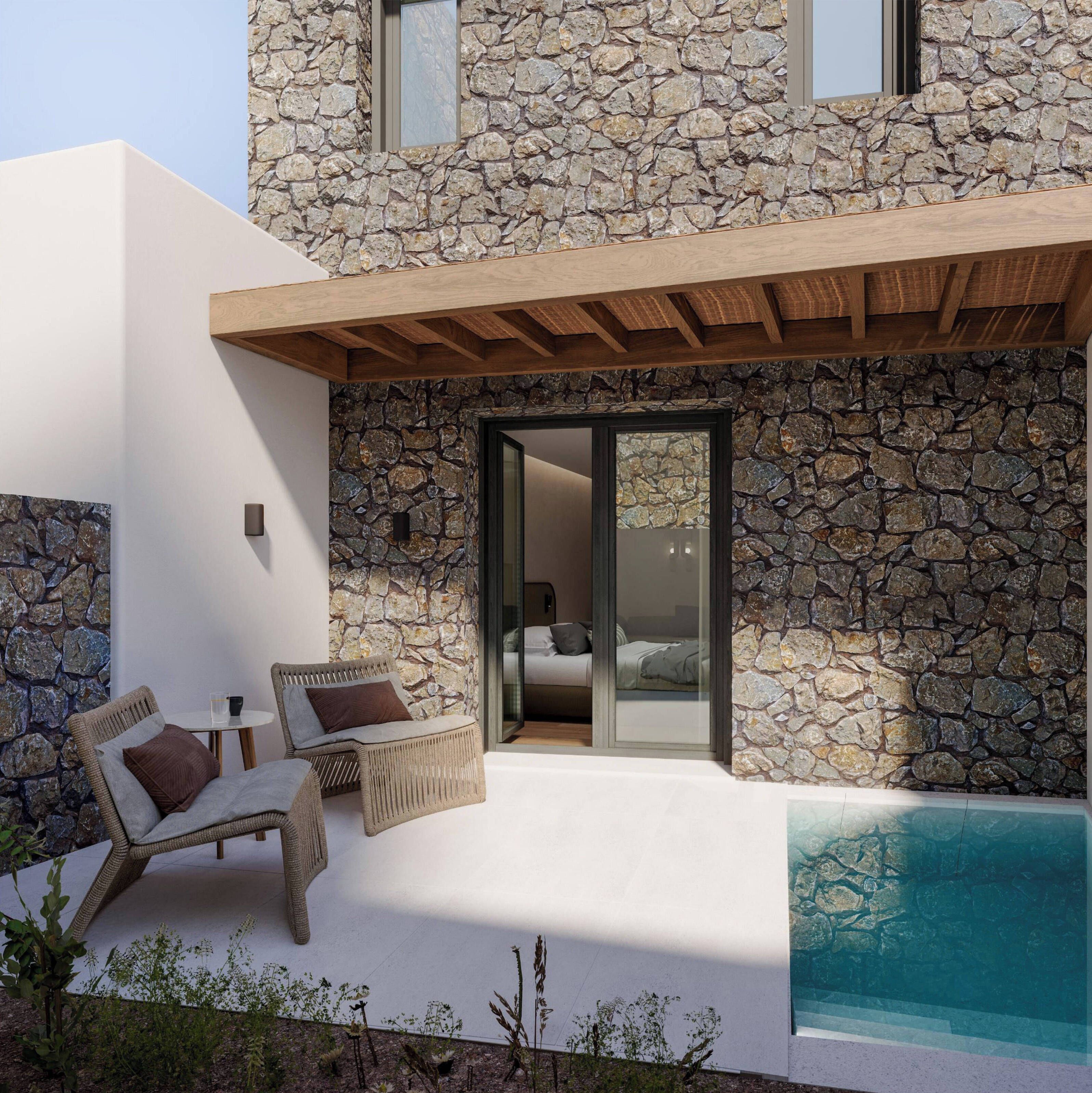 Une maison moderne avec une façade en pierre, une piscine et un patio couvert aménagé avec des meubles en osier.