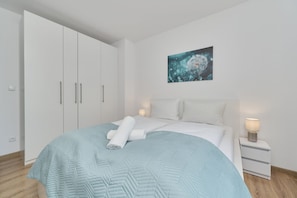 Una camera da letto con un letto, un'armadio bianco, comodini e un quadro appeso al muro.