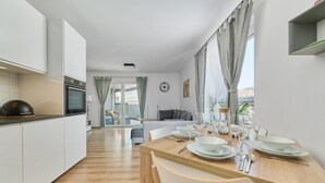 A modern kitchen with a dining area, wooden flooring, and a view of the living room.