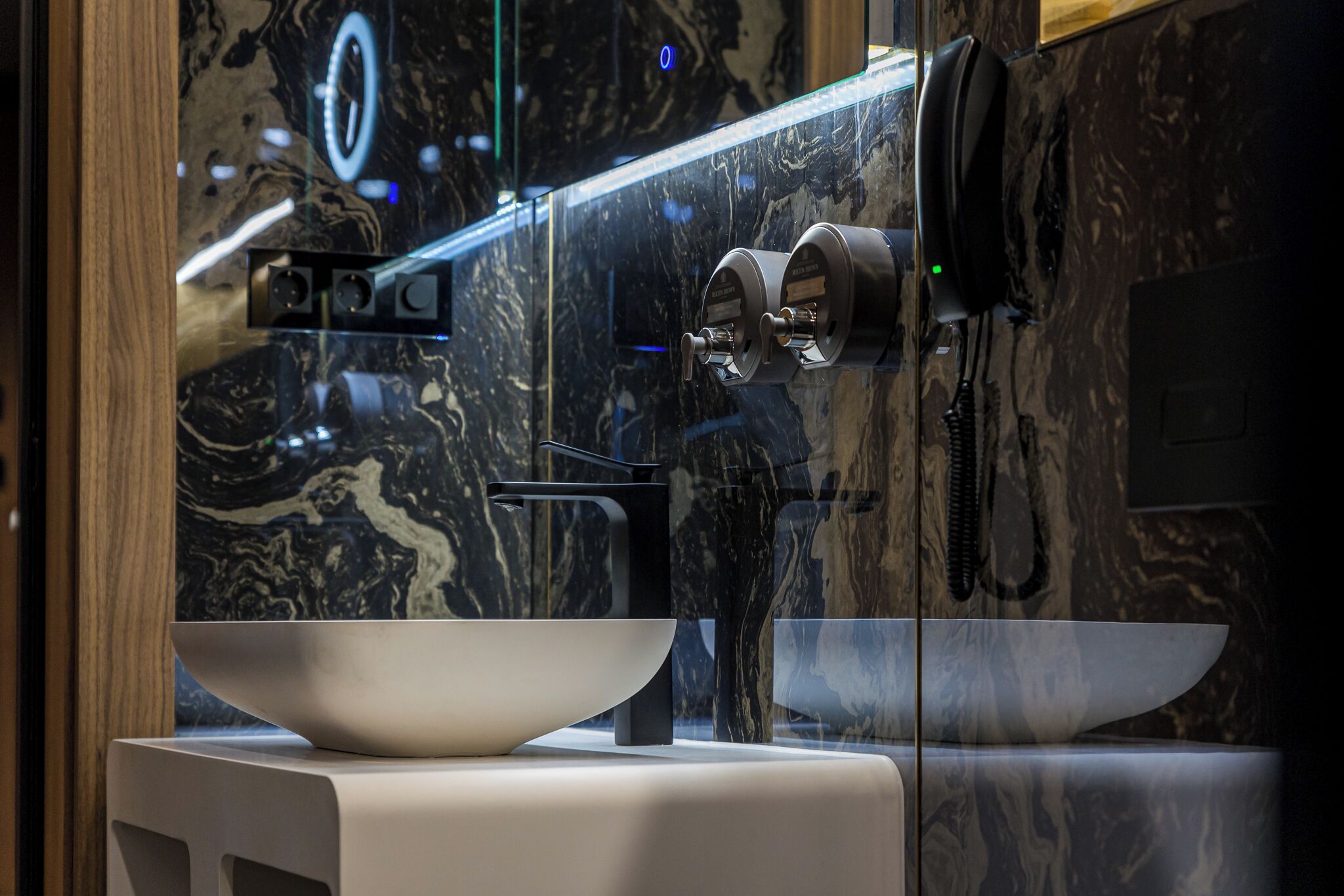 A modern bathroom with a marble backsplash, a large white sink, and a sleek faucet.