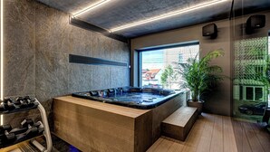 A modern spa area with a hot tub, exercise equipment, and a large window offering a view of the city. - Vibre Hotel (Cluj-Napoca)