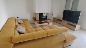 En moderne stue med en stor sofa, et sofabord, et fladskærms-tv og et lille skab.