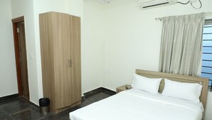 A bedroom with a bed, a wardrobe, a nightstand, and a window with curtains. - Shoba Comfort (Bengaluru)