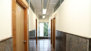 A hallway with wooden doors, a tiled floor, and a window at the end. - Shoba Comfort (Bengaluru)