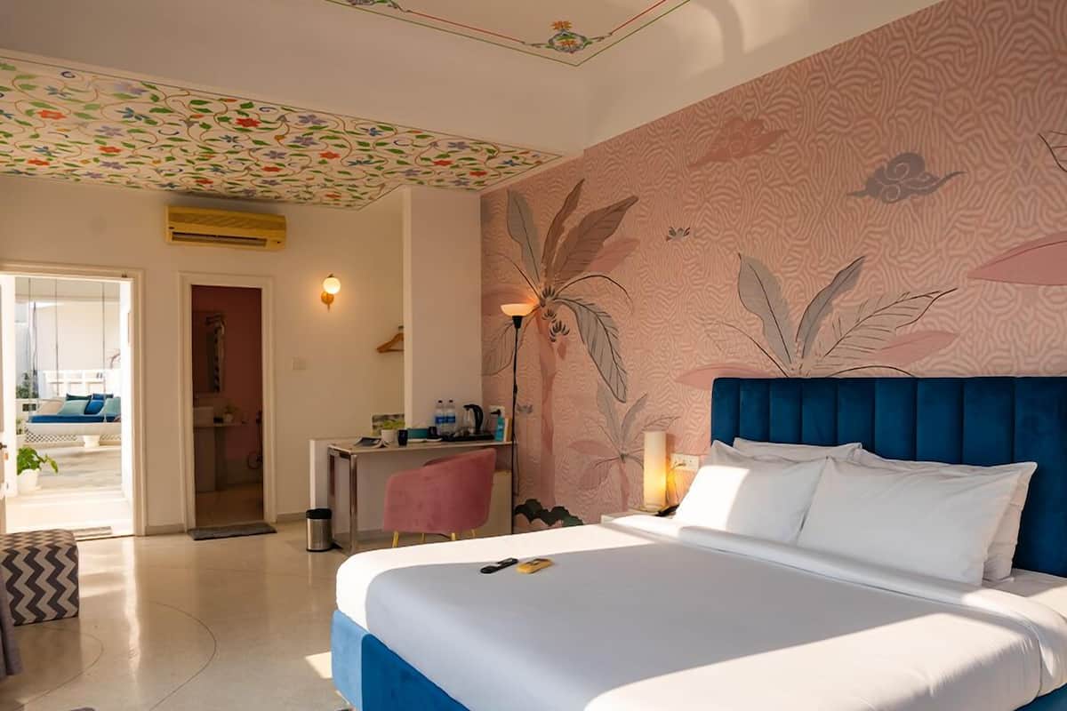 A modern hotel room with a large bed, a desk, and a view of the outside.