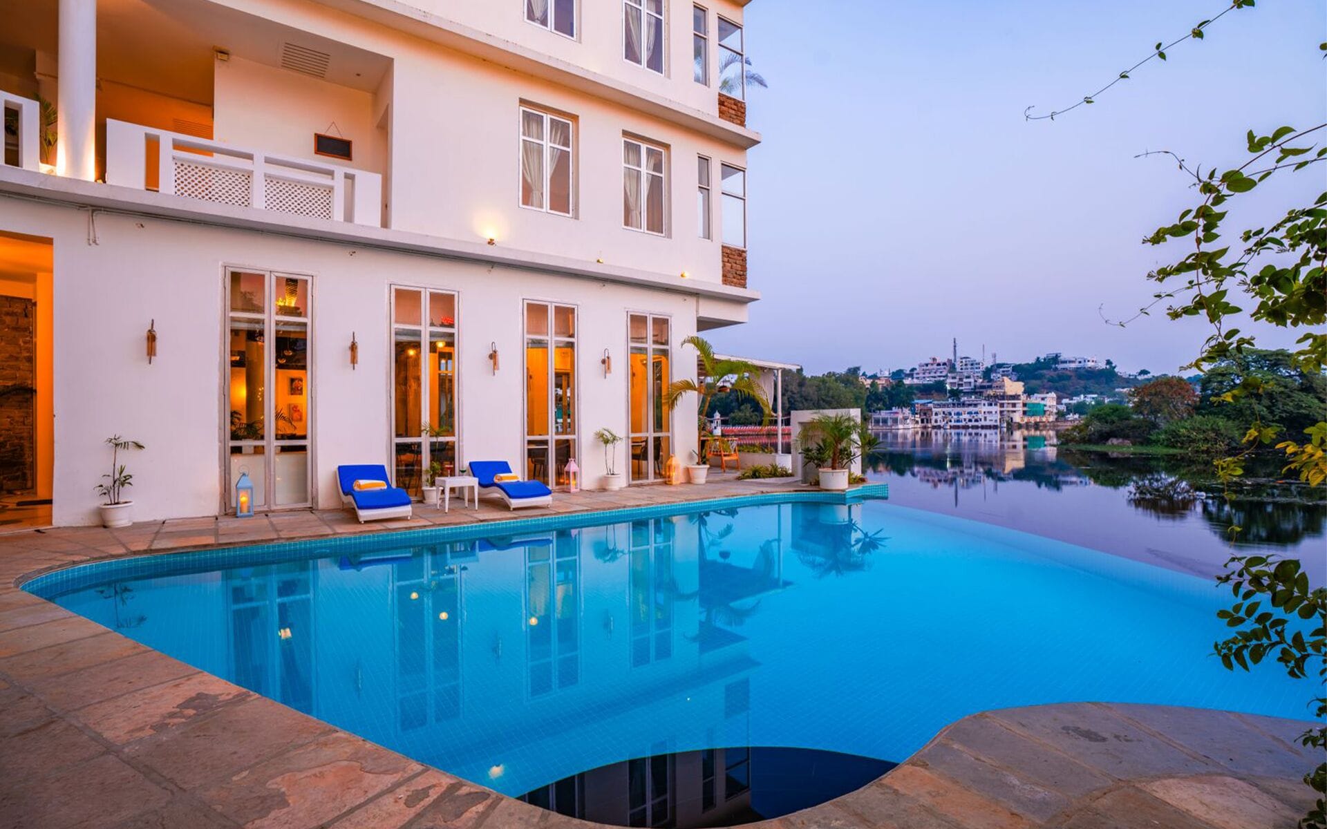 A modern hotel with a pool, large windows, and a view of a cityscape.