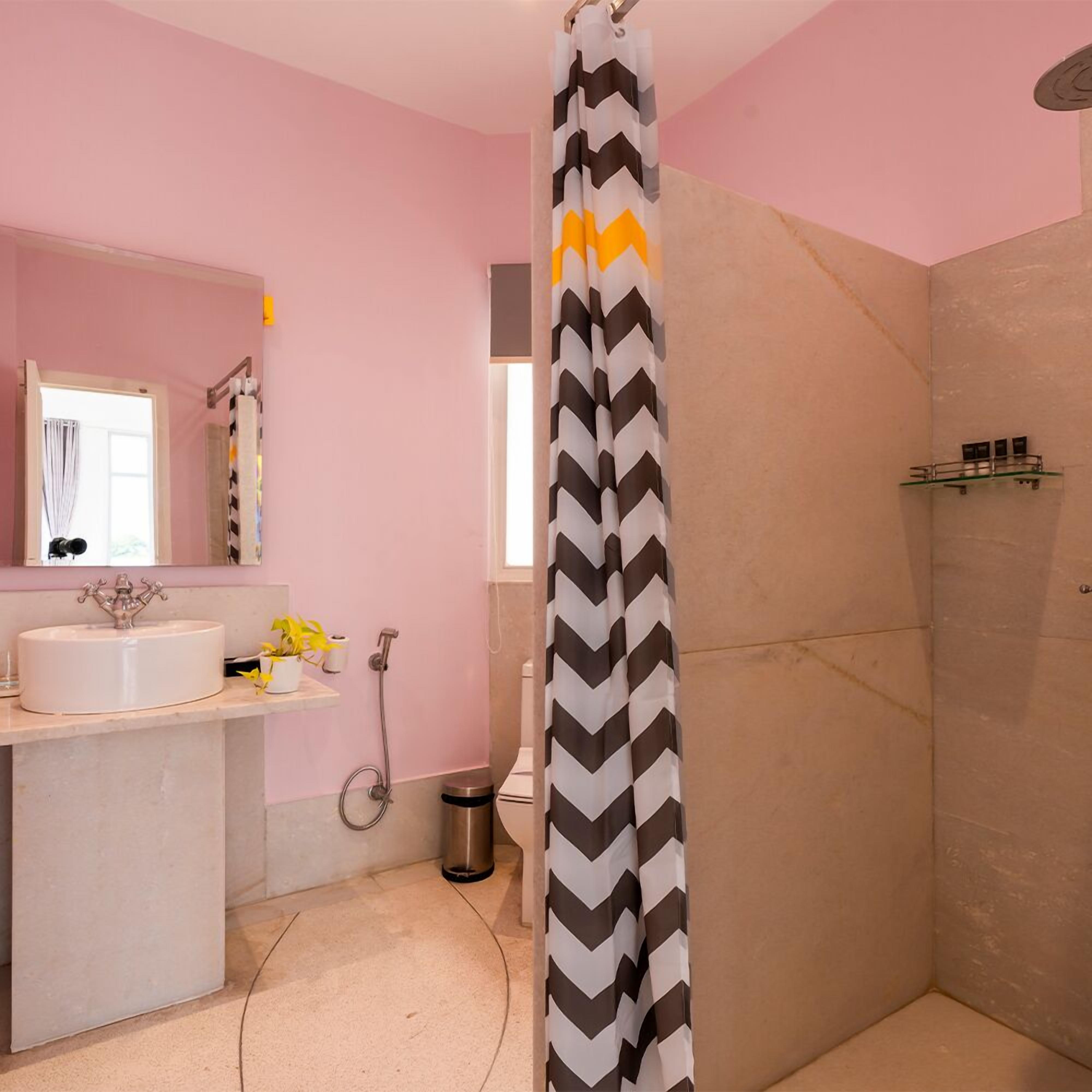 A bathroom with a shower curtain, sink, mirror, and a small shelf with toiletries.
