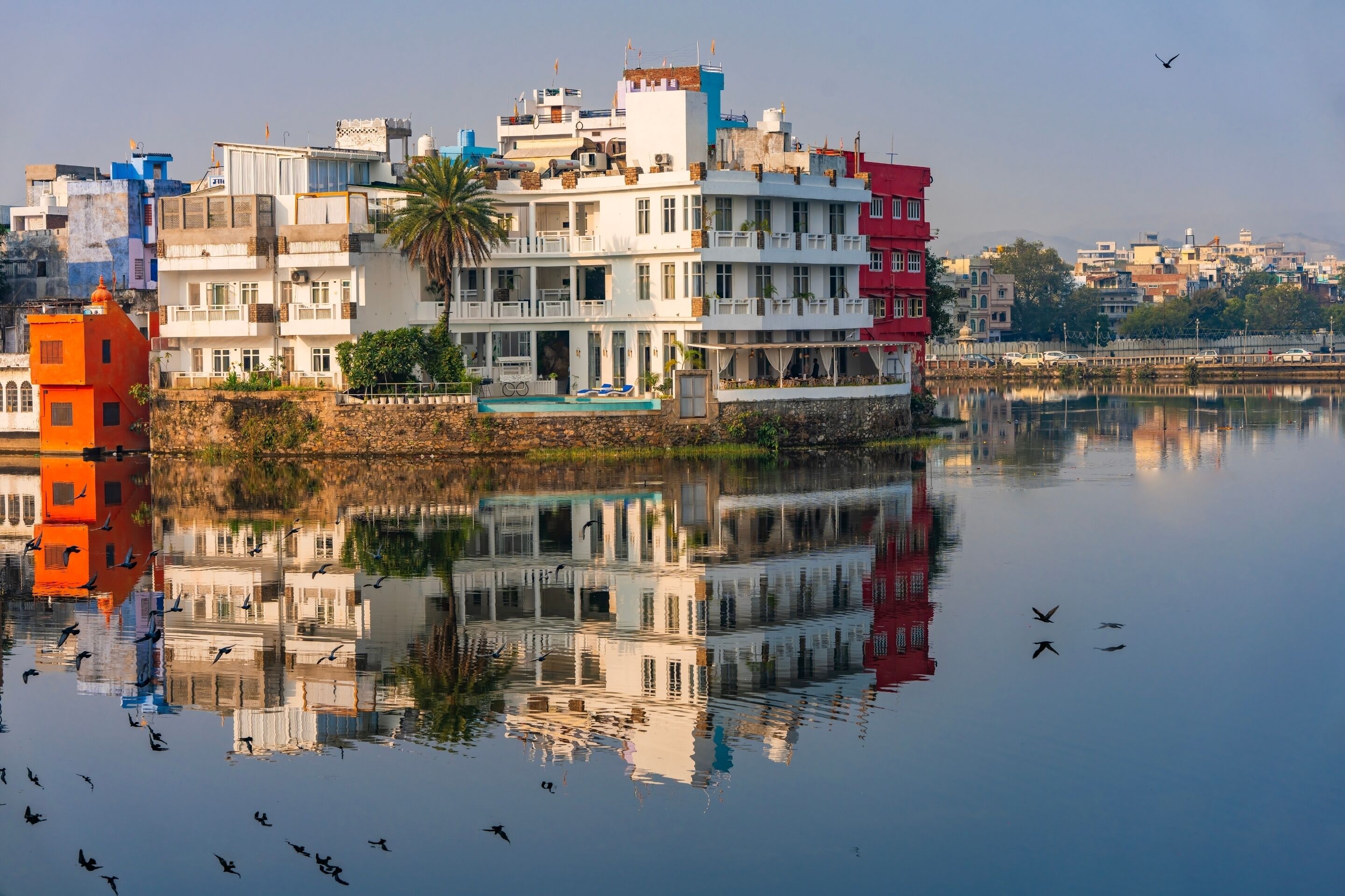Un edificio frente al agua con varios balcones y su reflejo en el agua.