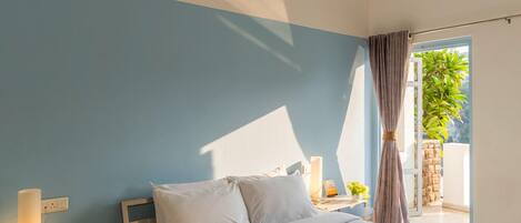 Un dormitorio con cama, mesitas de noche, lámpara y ventana con cortinas.